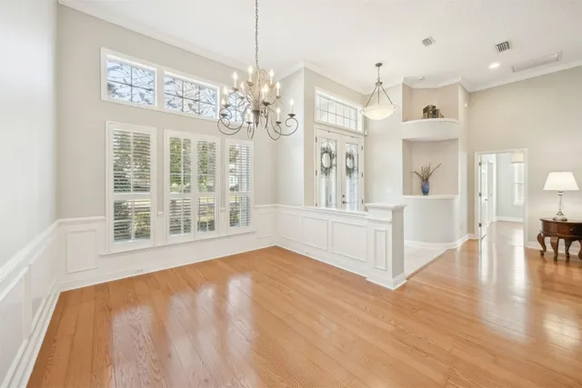 a view of an empty room with wooden floor and a chandelier
