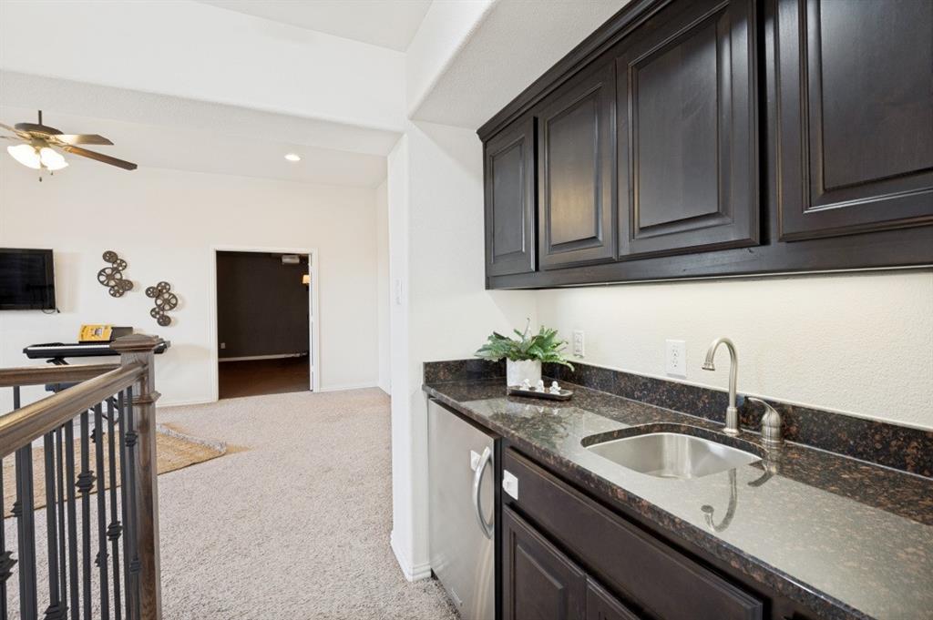 14215 Raspberry Lane Frisco, TX 75035 - Photo 18 of 30 Built-in wet bar featuring dark cabinetry, a stainless steel sink, and a dark stone countertop