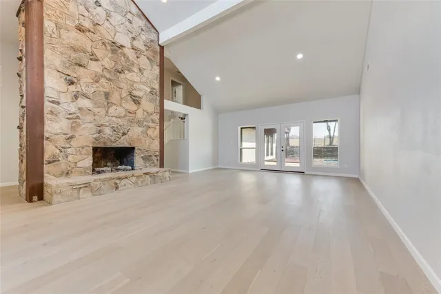 an empty room with windows and fireplace