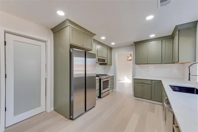 a kitchen with stainless steel appliances granite countertop a refrigerator a sink and a stove