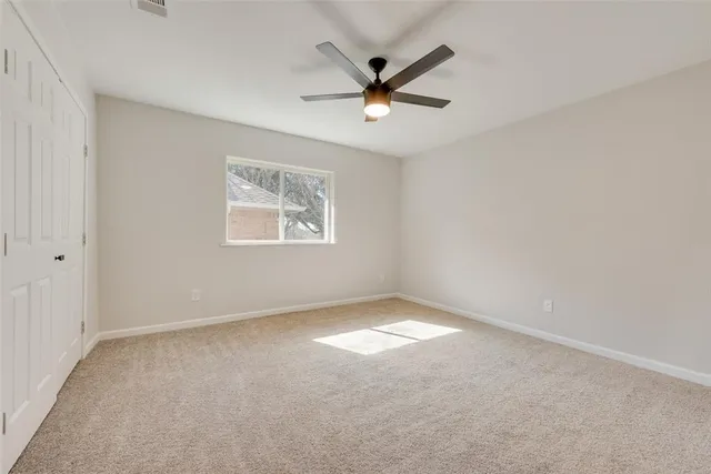 an empty room with a window and a fan