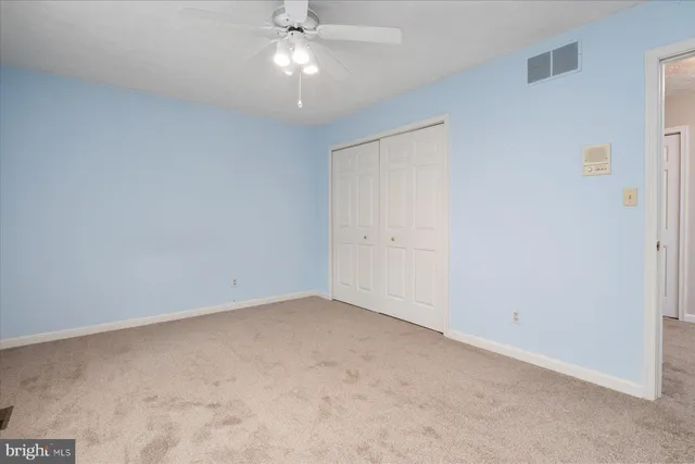 an empty room with a chandelier fan and closet area