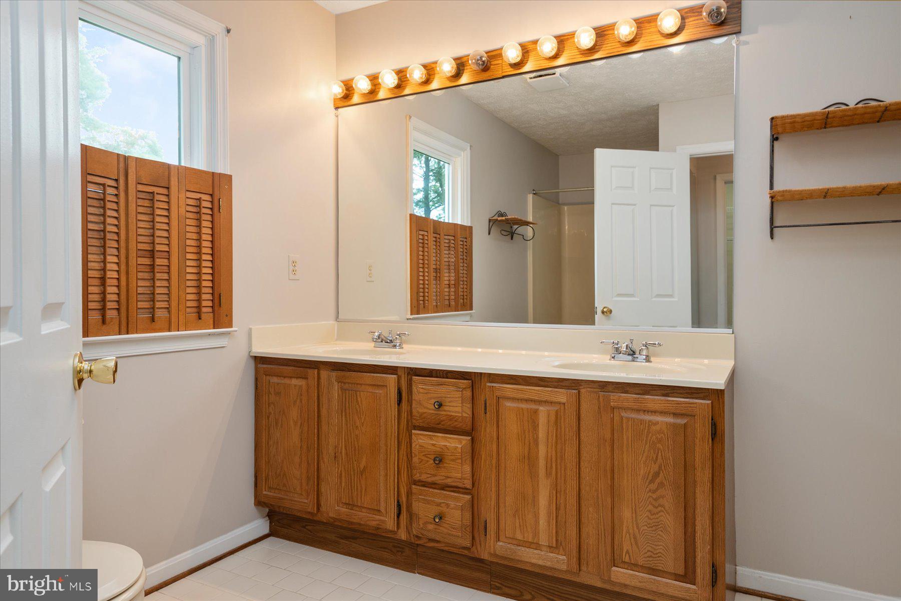 7907 Poplar Grove Road Severn, MD 21144 - Photo 28 of 38 a bathroom with a double vanity sink and a mirror
