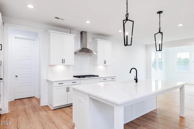 a kitchen with a stove a sink a refrigerator and wooden floor