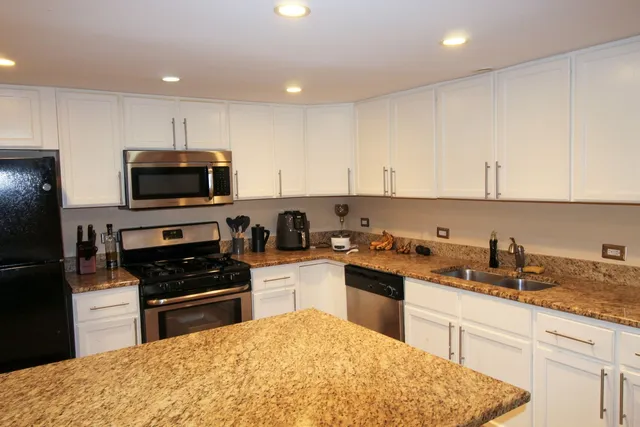a kitchen with granite countertop a sink a stove and cabinets