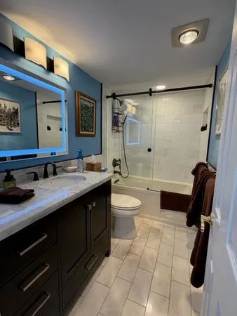 a bathroom with a granite countertop sink a toilet a mirror and shower