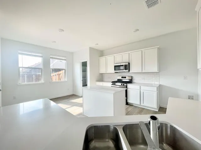 a kitchen with sink a microwave and cabinets