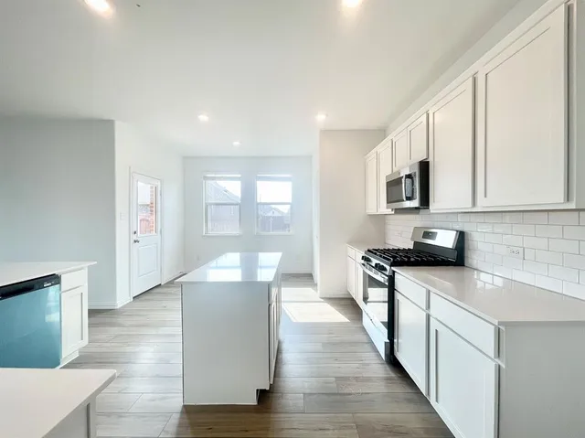 a large kitchen with stainless steel appliances granite countertop a lot of counter space and wooden floors