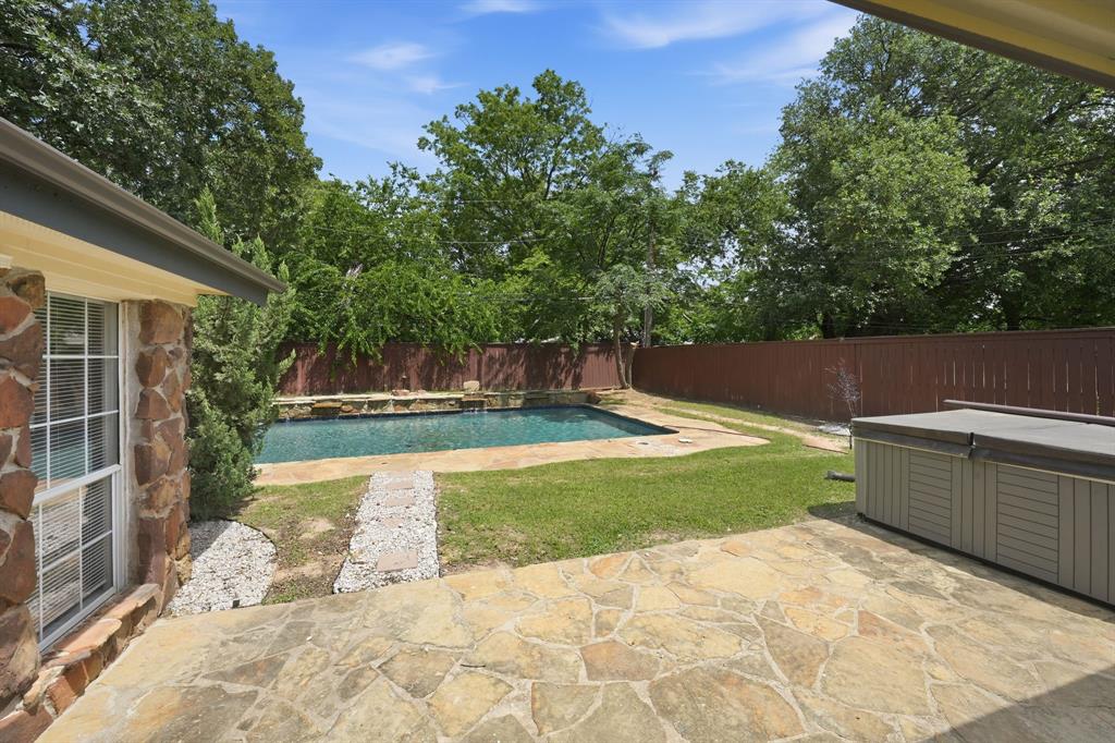 1108 Billie Ruth Lane Hurst, TX 76053 - Photo 23 of 27 Outdoor living area featuring a stone patio, an in-ground swimming pool with rock waterfall, and a hot tub