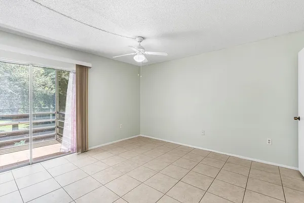 an empty room with windows and ceiling fan