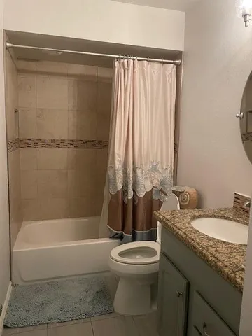 a bathroom with a granite countertop bathtub shower sink vanity and toilet