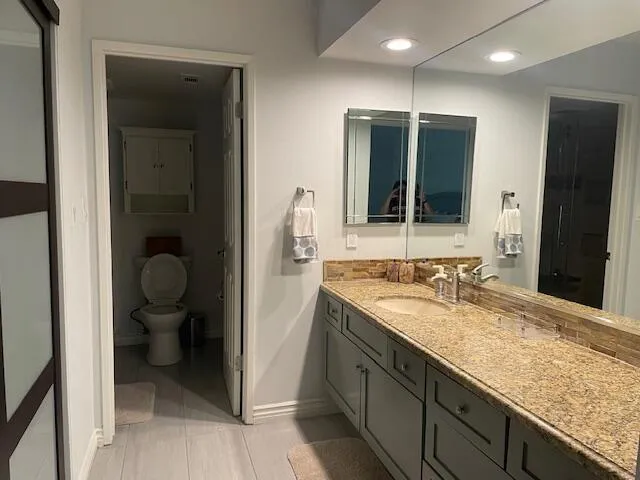 a bathroom with a granite countertop sink toilet and shower