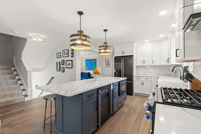 a kitchen with granite countertop a stove a sink dishwasher a refrigerator and white cabinets with wooden floor