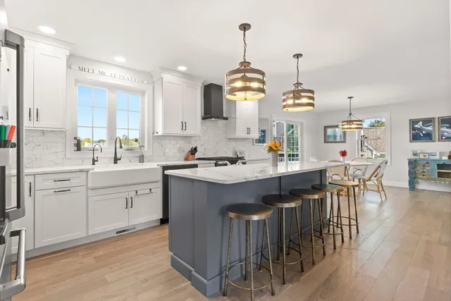 a kitchen with kitchen island granite countertop a sink a center island a stove and a wooden floors