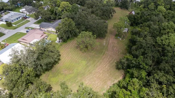 an aerial view of residential house with outdoor space and trees all around