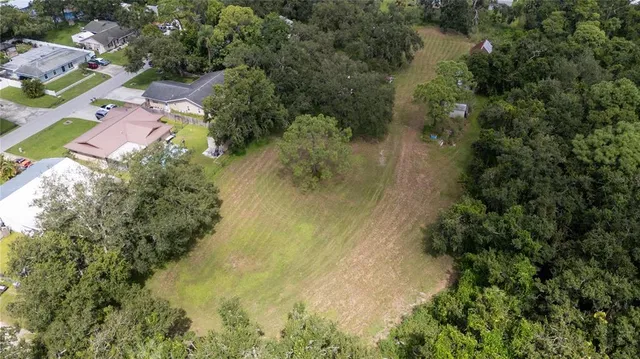 an aerial view of residential house with outdoor space and trees all around