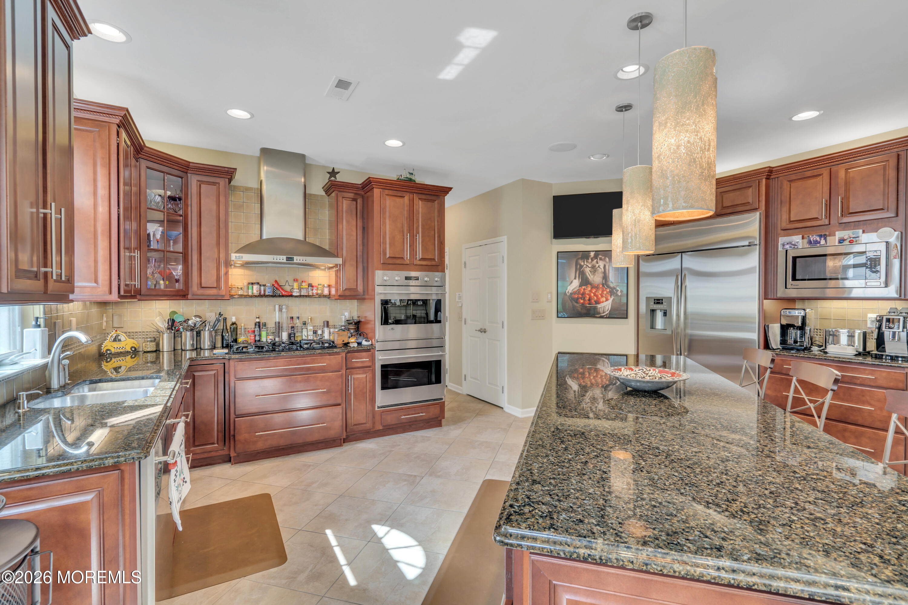 15 Enclave Boulevard Lakewood, NJ 08701 - Photo 32 of 81 a kitchen with stainless steel appliances granite countertop a stove top oven a sink a dining table and chairs with wooden floor
