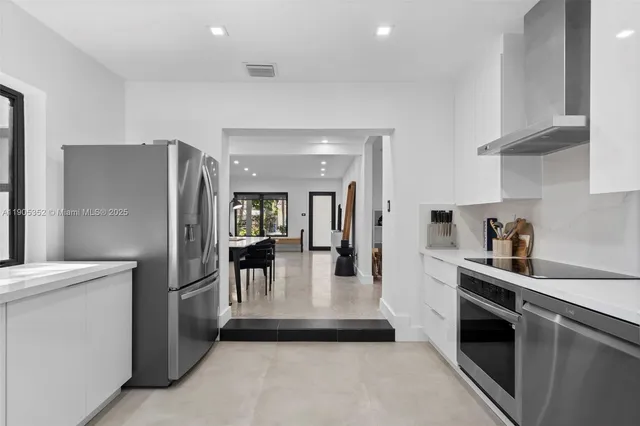 a kitchen with stainless steel appliances granite countertop a refrigerator a stove and a sink with cabinets