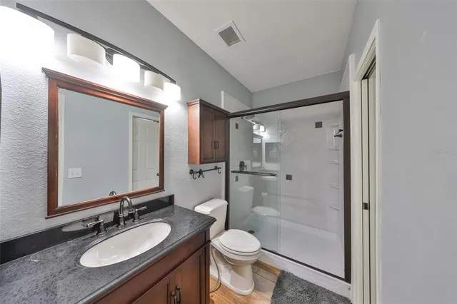 a bathroom with a granite countertop sink toilet a mirror a bathtub and shower