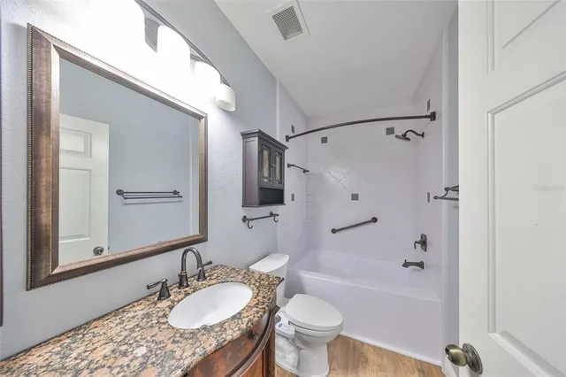 a bathroom with a granite countertop sink toilet mirror and shower