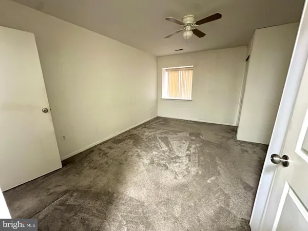 an empty room with a window and a fan