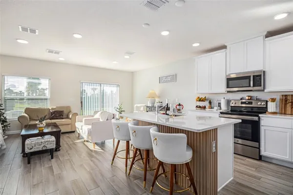 a kitchen with stainless steel appliances granite countertop a stove top oven a sink dishwasher a dining table and chairs with wooden floor