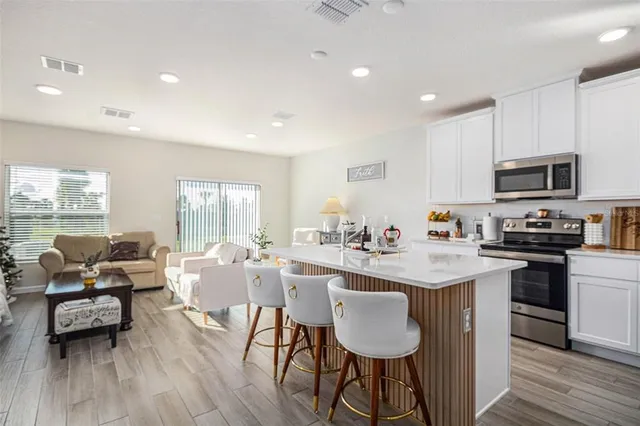 a kitchen with stainless steel appliances granite countertop a stove top oven a sink dishwasher a dining table and chairs with wooden floor