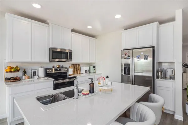 a kitchen with stainless steel appliances a refrigerator a sink a stove top oven a counter space and cabinets