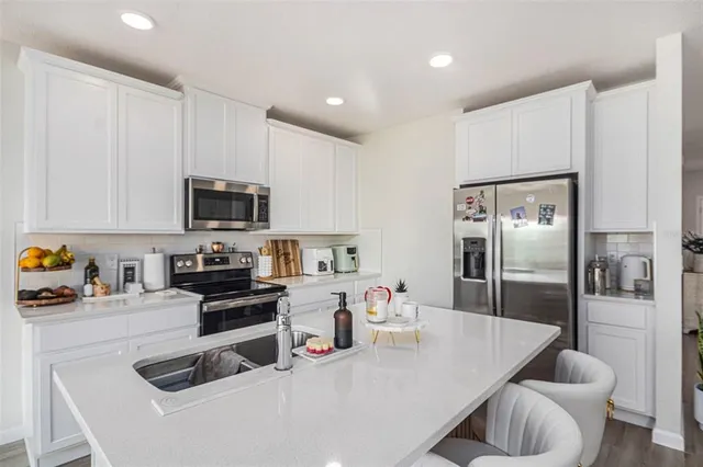 a kitchen with stainless steel appliances a refrigerator a sink a stove top oven a counter space and cabinets