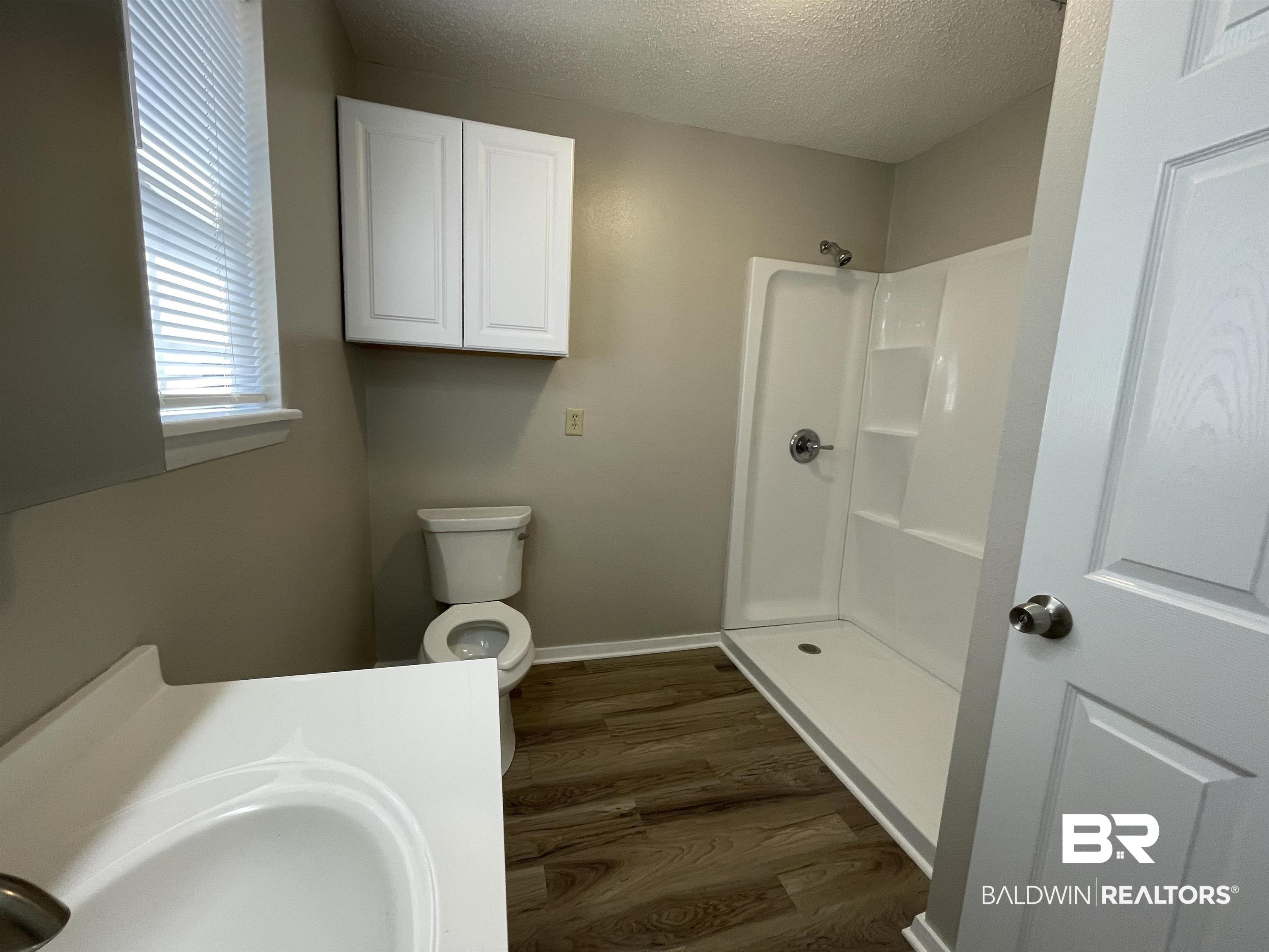 28414 Highway 31 Flomaton, AL 36441 - Photo 7 of 11 Bathroom featuring toilet, wood finished floors, a textured ceiling, a shower, and a sink