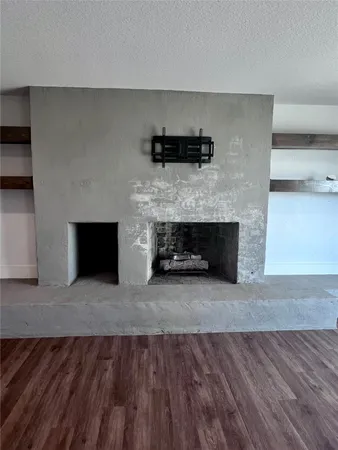an empty room with wooden floor a ceiling fan and a fireplace