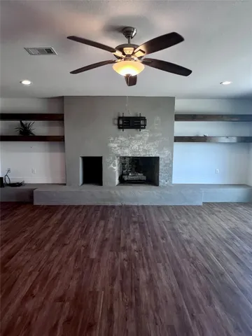 an empty room with wooden floor a ceiling fan and a fireplace