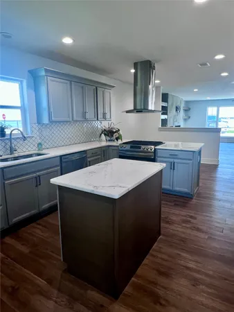 a kitchen with stainless steel appliances granite countertop a sink a stove and a wooden floors