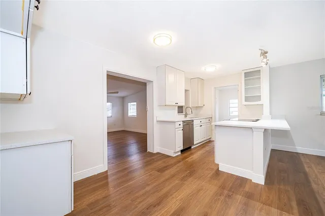 a kitchen with white cabinets and wooden floor