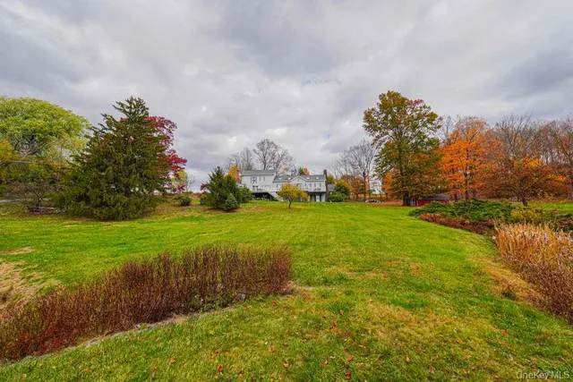 a view of a house with a big yard plants and large trees