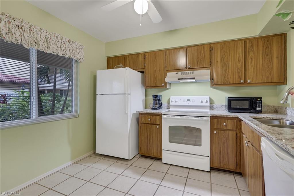 1025 Foxfire Lane, Unit 110 Naples, FL 34104 - Photo 12 of 48 a kitchen with a stove top oven sink and cabinets