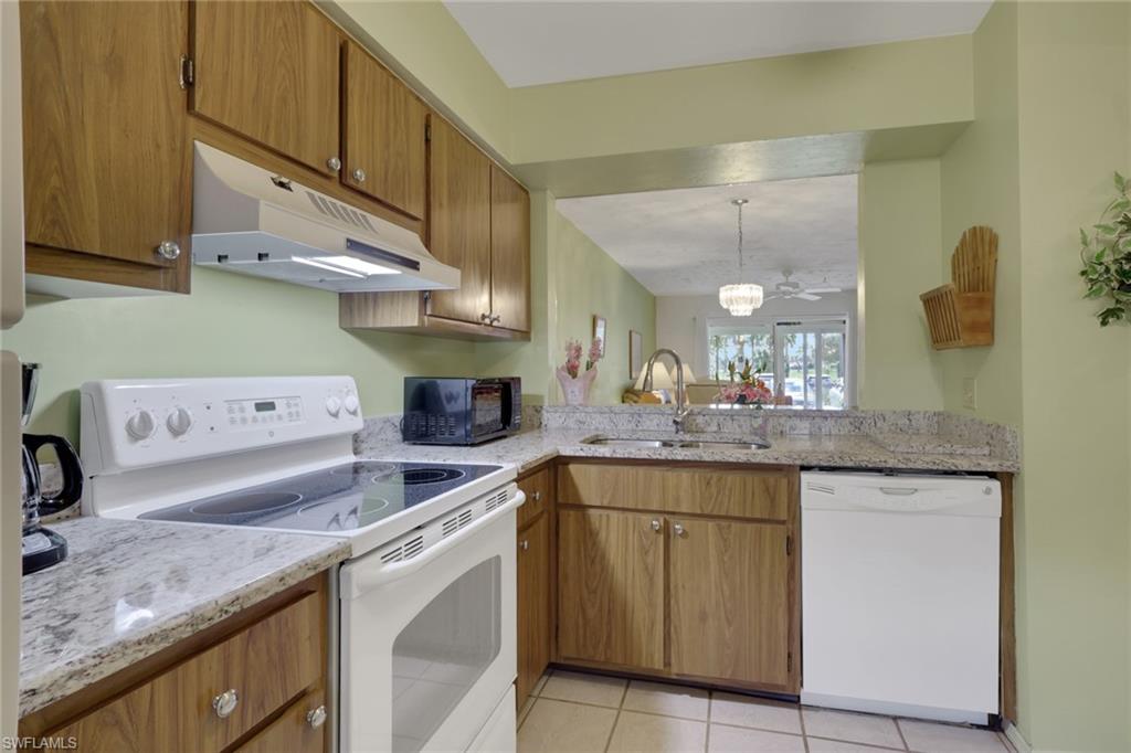 1025 Foxfire Lane, Unit 110 Naples, FL 34104 - Photo 14 of 48 a kitchen with a sink dishwasher and cabinets with wooden floor