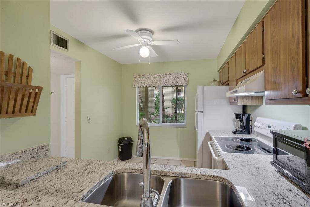1025 Foxfire Lane, Unit 110 Naples, FL 34104 - Photo 15 of 48 a kitchen with stainless steel appliances granite countertop a sink stove and refrigerator