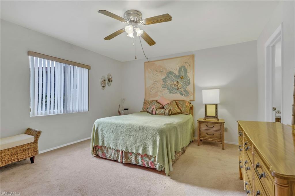 1025 Foxfire Lane, Unit 110 Naples, FL 34104 - Photo 20 of 48 a bedroom with a bed and a chandelier