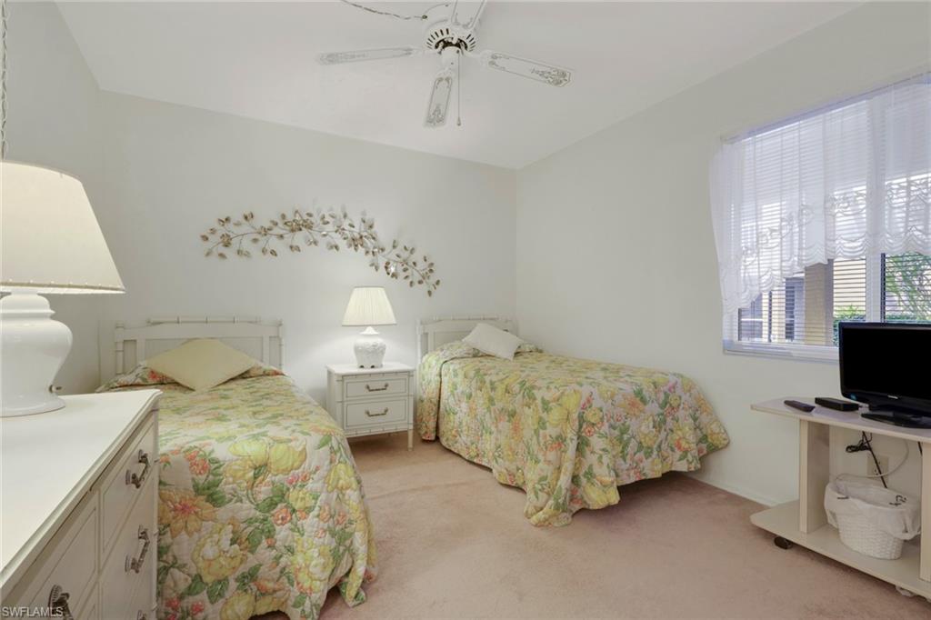 1025 Foxfire Lane, Unit 110 Naples, FL 34104 - Photo 23 of 48 a spacious bedroom with two bed and a flat screen tv