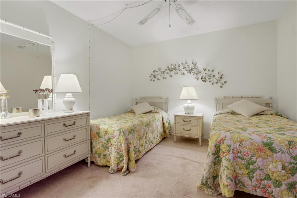 1025 Foxfire Lane, Unit 110 Naples, FL 34104 - Photo 24 of 48 a spacious bedroom with a bed and a chandelier