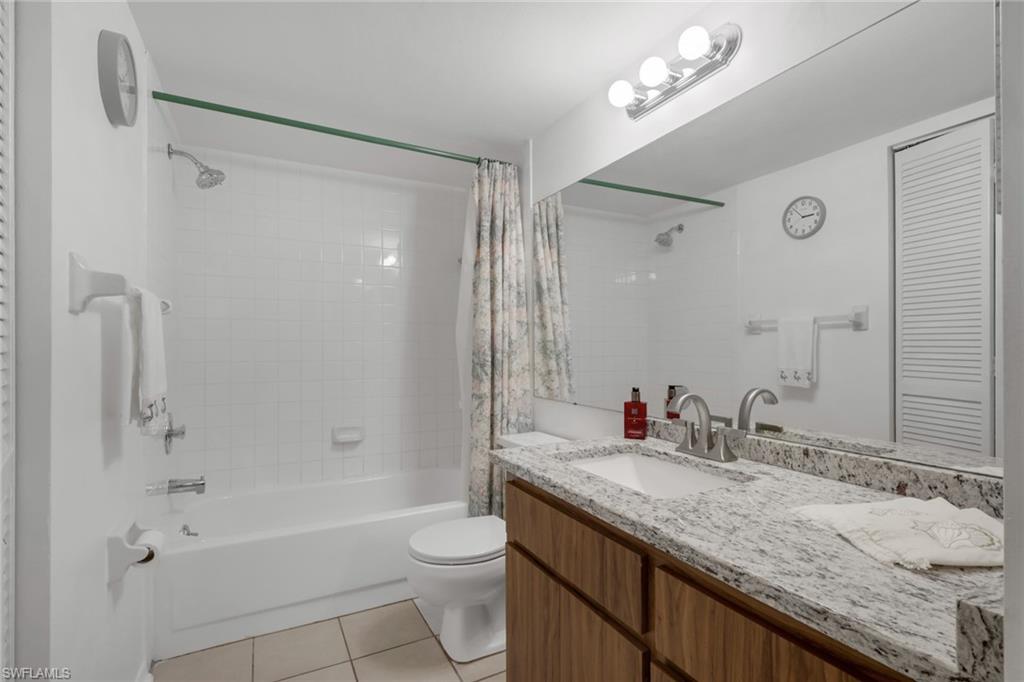 1025 Foxfire Lane, Unit 110 Naples, FL 34104 - Photo 25 of 48 a bathroom with a granite countertop sink a toilet a mirror and shower