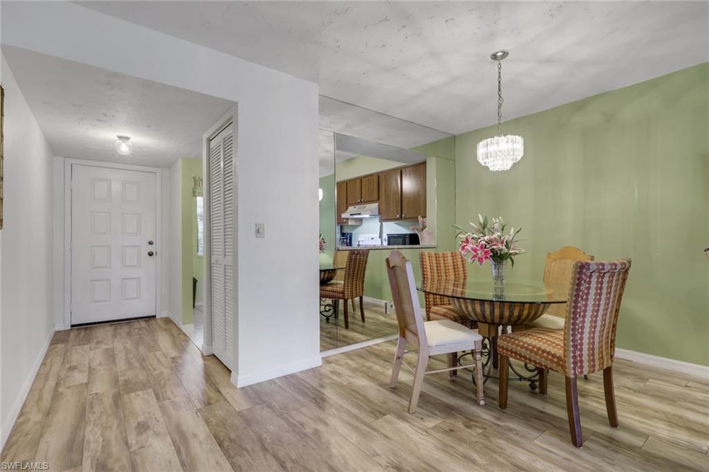 1025 Foxfire Lane, Unit 110 Naples, FL 34104 - Photo 9 of 48 a view of a dining room with furniture and wooden floor