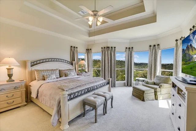 a bedroom with a bed couch and large windows