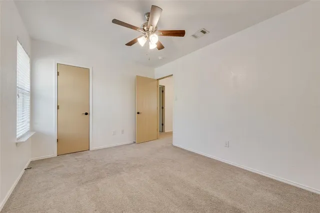 an empty room with a ceiling fan and a window