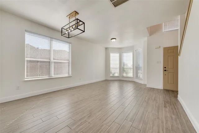 an empty room with wooden floor cabinet and windows