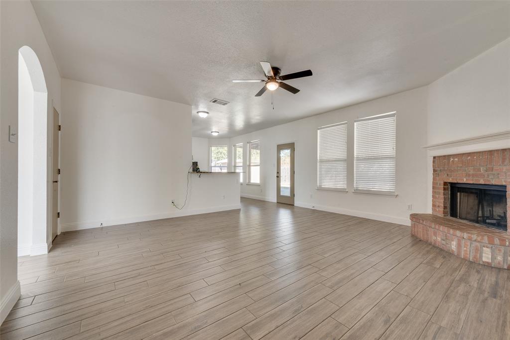 2701 Wildridge Court Fort Worth, TX 76108 - Photo 8 of 26 an empty room with wooden floor fireplace and windows