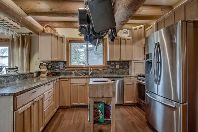 a kitchen with stainless steel appliances a sink cabinets and a wooden floor