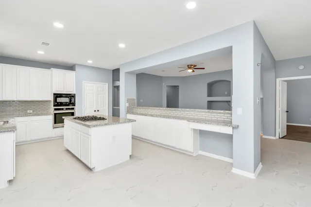 a large white kitchen with kitchen island a sink a stove and a refrigerator