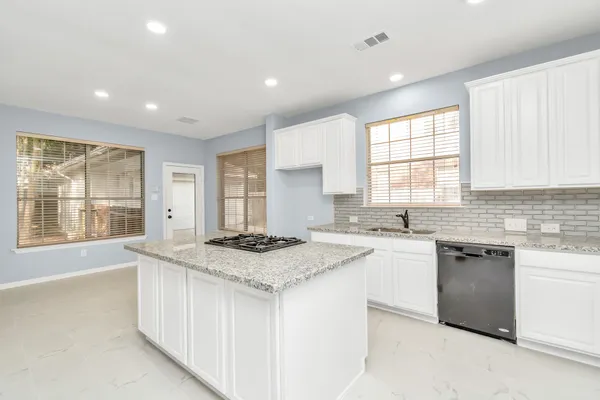 a kitchen with a stove a sink a center island and windows